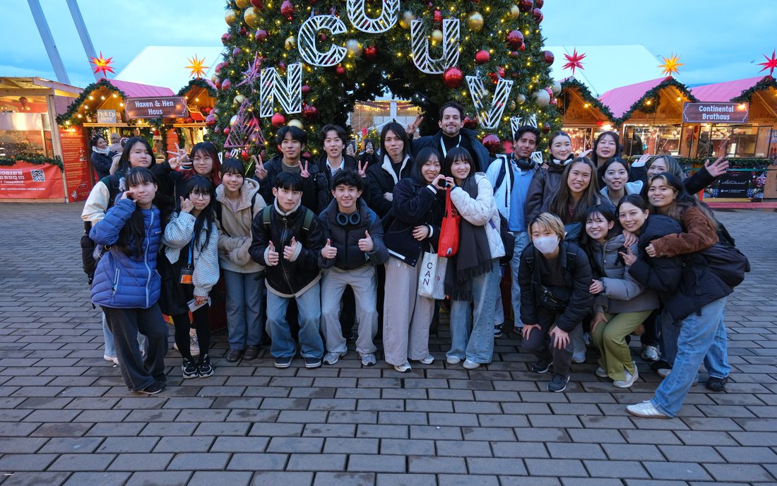 Estudiantes internacionales celebrando frente al árbol de Navidad en un mercado de Vancouver