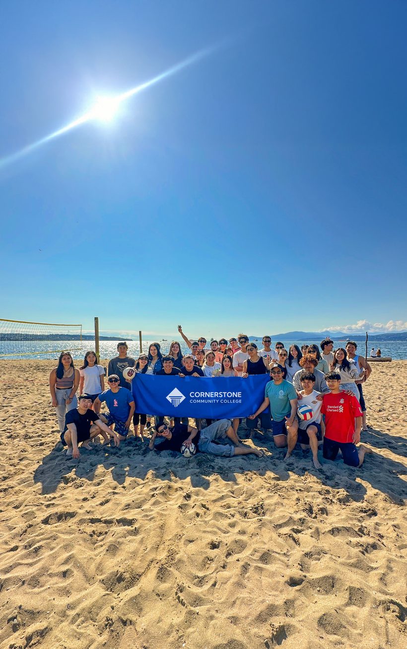 Estudiantes de Cornerstone College (CICCC) en una playa de Vancouver con la bandera del colegio