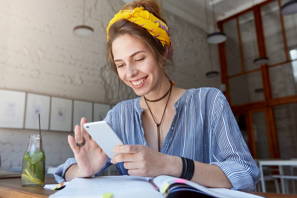 Estudiante sonriendo mientras se registra desde su celular